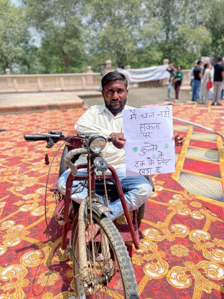 A man on a tricycle holds a handwritten sign.